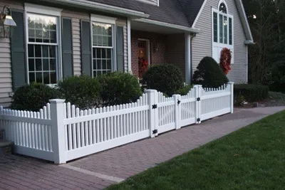White vinyl picket fence across a home's front yard