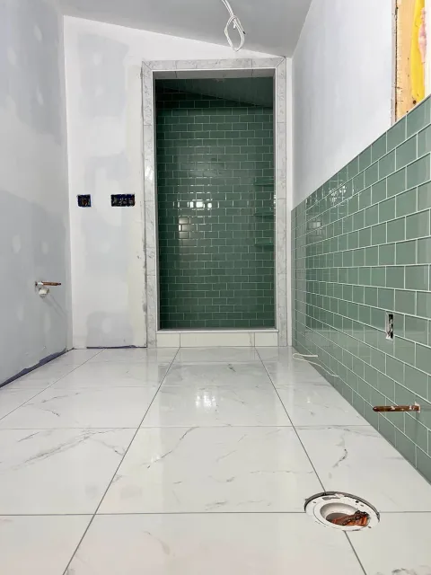 A bathroom under construction with green tiles and white tiles.