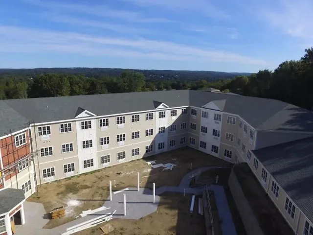 An aerial view of a large apartment building under construction surrounded by trees.