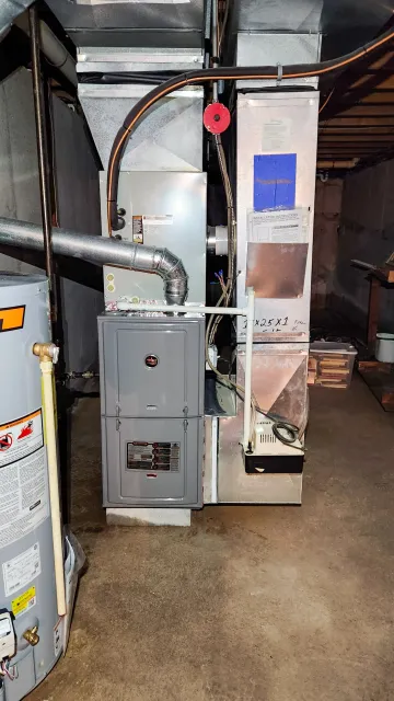 Furnace and water heater in a basement utility room.