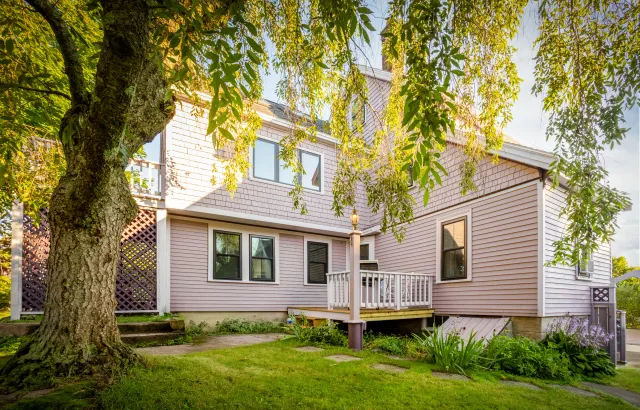 Garden-side exterior with mauve siding, light trim, purple lattice, and a small deck