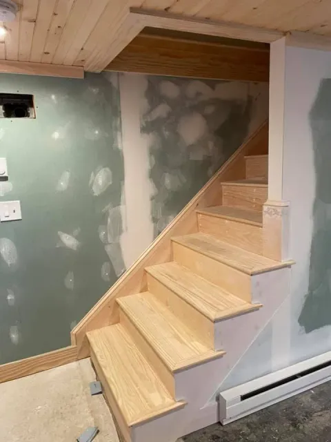 A wooden staircase is being built in a basement.