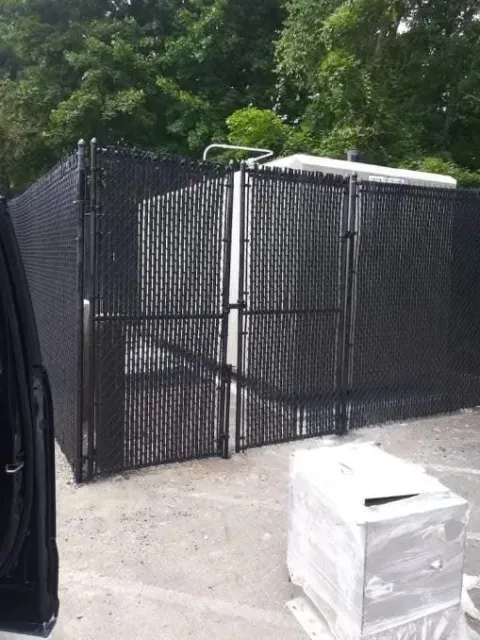 A man is using a drill to install a chain link fence.