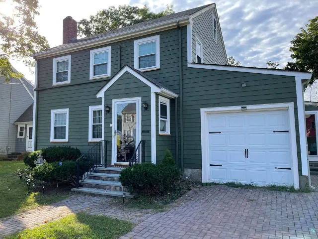 a green house with white trim and a white garage door