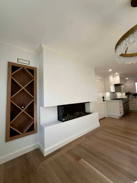 Modern living room with fireplace, built-in wine rack, and light wood flooring.
