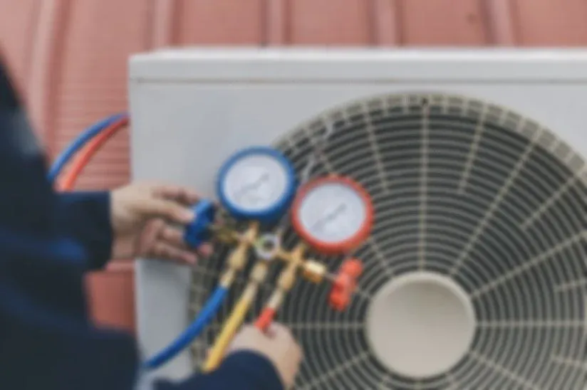 Technician checking air conditioning unit with pressure gauges