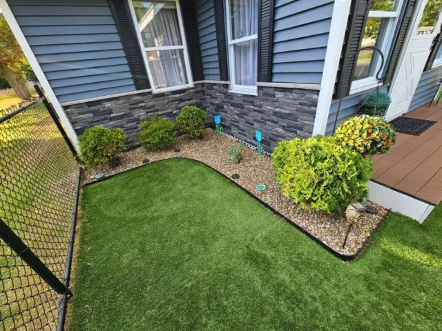 Fresh mulch bed with crisp edging beside a stone-fronted home in Hudson, NH