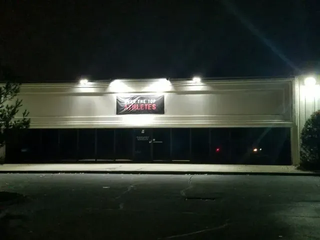 A dark night view of a strip mall storefront with a sign that reads