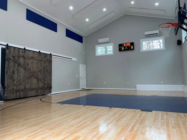 Finished home sport court with hardwood floor and sliding barn door