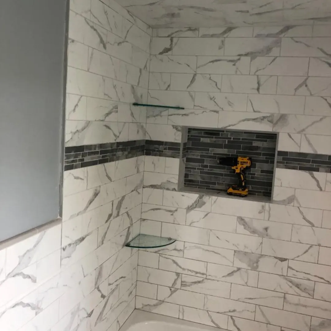 Marble subway tile shower walls with mosaic accent band and niche by Link Services Pro in Westborough, MA