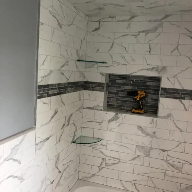 Marble subway tile shower walls with mosaic accent band and niche by Link Services Pro in Westborough, MA