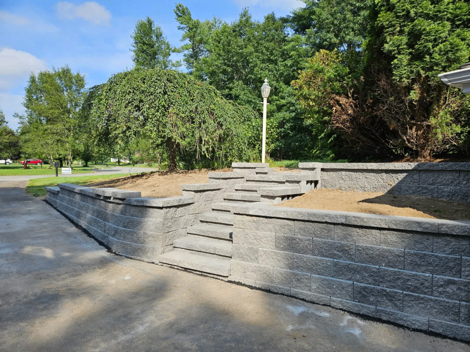 Tiered retaining wall with stone steps and capstones along a driveway in Boston, MA
