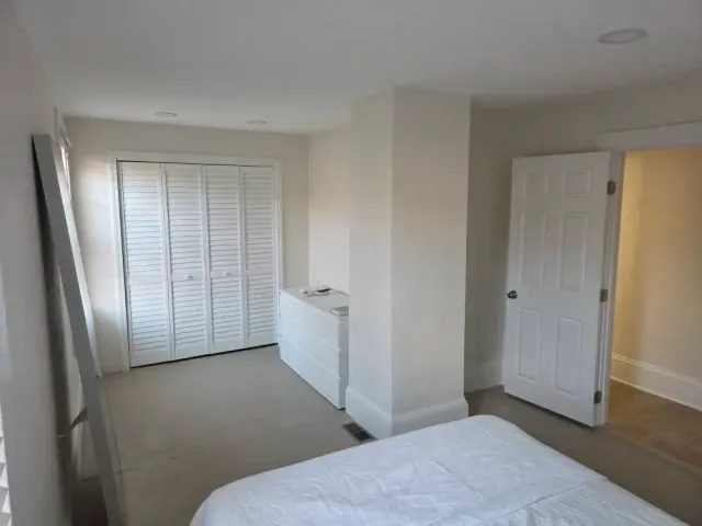 Empty beige bedroom with bed, closet doors, and open doorway to hall