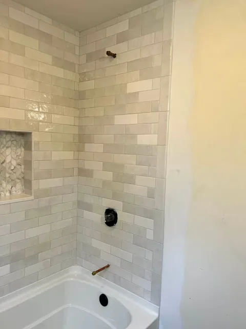 A bathroom with white tiles and a bathtub.