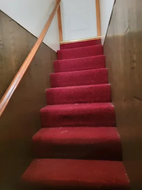 Before of Old Stairs, with red carpeting and old wooden paneling on the walls.