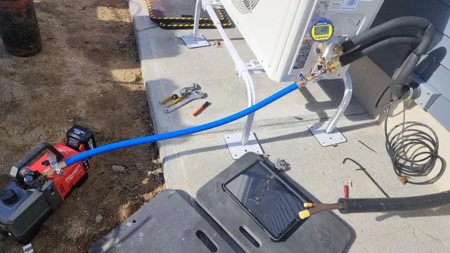 A blue hose is connected to a compressor on a concrete surface.