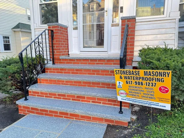 Brick front steps with black railings and a yellow sign in front of a house.