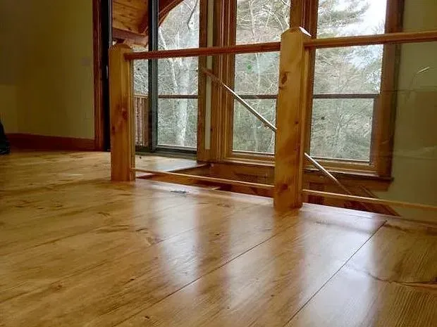 Wooden floor with a railing overlooking a window, natural light.