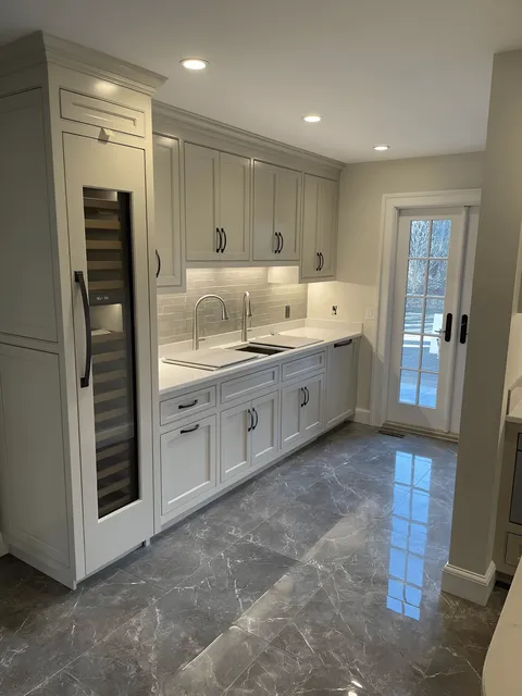 A Stylish Kitchen Showcasing Pristine White Cabinets And Luxurious Marble Countertops, Exuding A Contemporary And Clean Design.