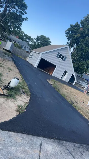 New asphalt driveway leading to a detached two-story garage