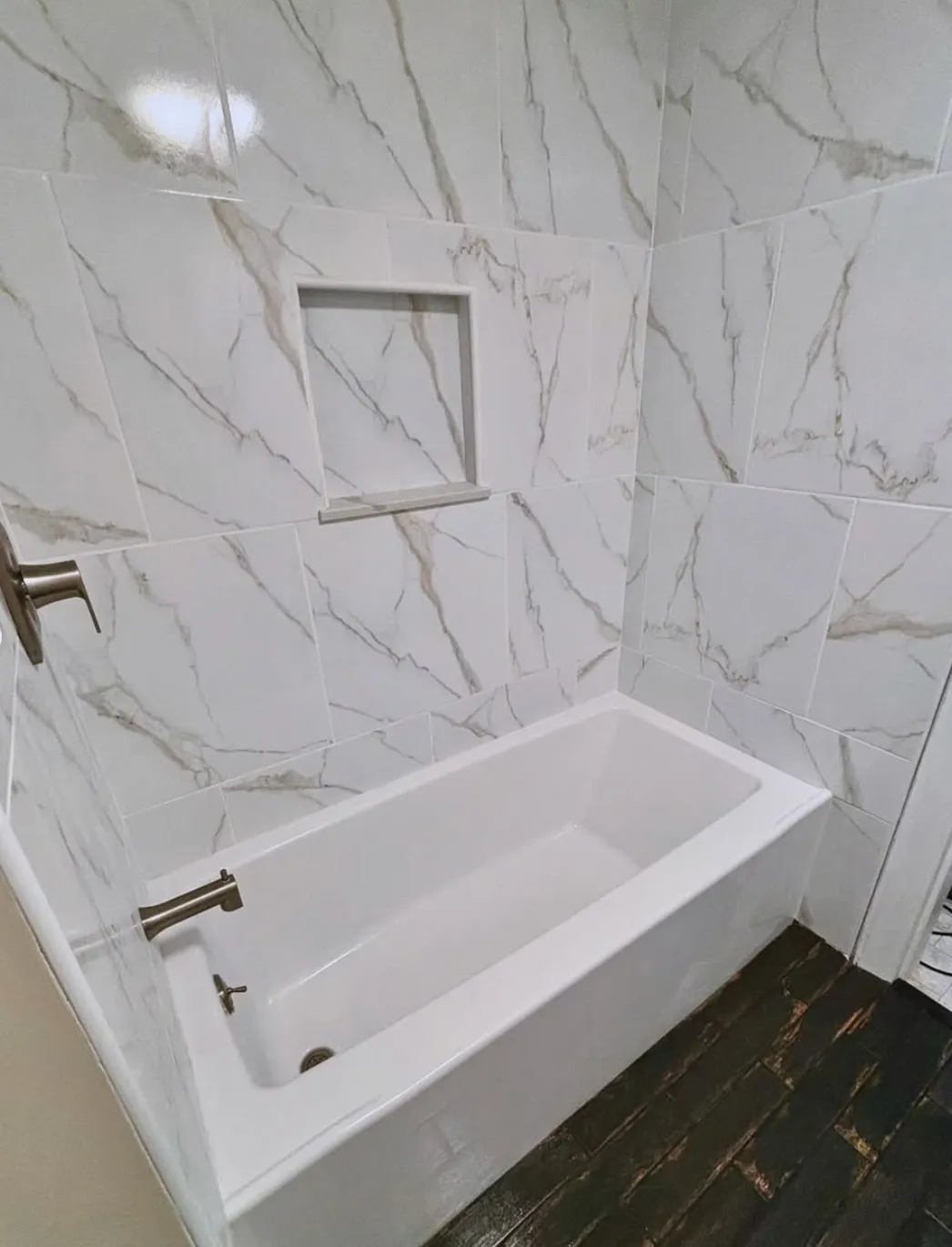 Modern bathroom with a white bathtub and marble wall tiles.