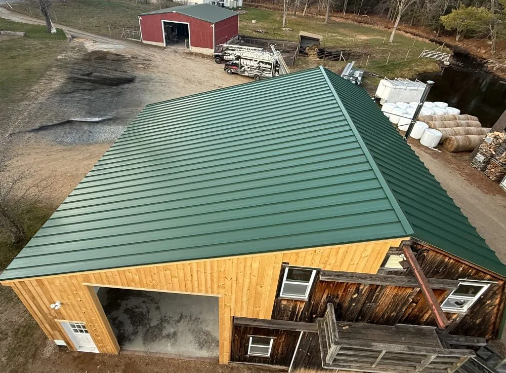 Green standing seam metal roofing installed on a barn structure in New Hampshire.