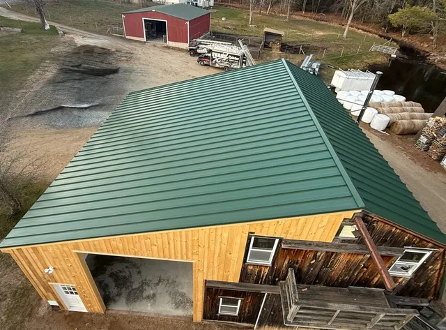 Green standing seam metal roofing installed on a barn structure in New Hampshire.