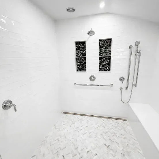 Bright white accessible shower with bench, grab bars, handheld sprayer, and tiled floor