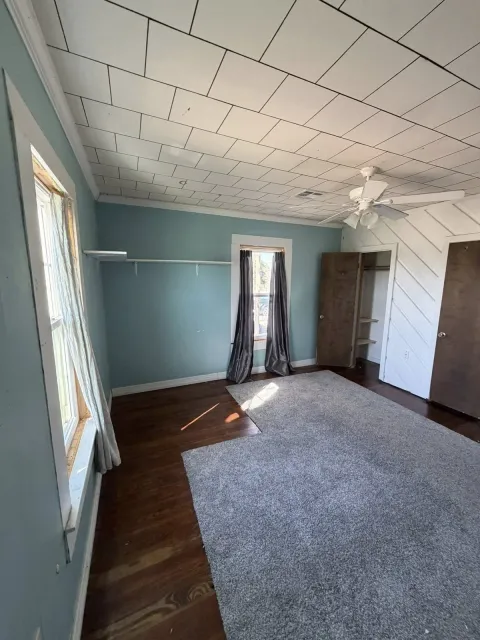 Bedroom before renovation with teal walls, dark hardwood floors, closet rod, and angled ceiling