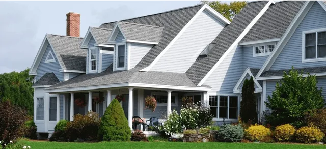 A charming white house with a spacious porch and lush landscaping.