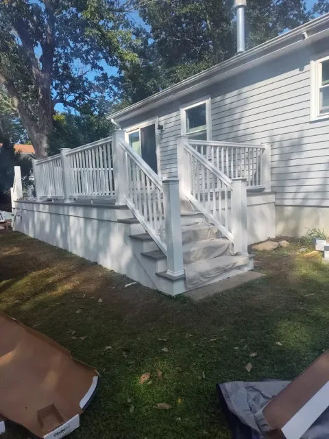 White deck stairs with railings leading to a house exterior on a grassy yard.