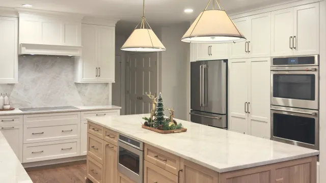 Warm white cabinetry paired with a natural oak island and full-height Taj Mahal Quartzite backsplash.