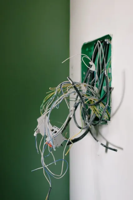 A bunch of wires sticking out of a hole in a wall.