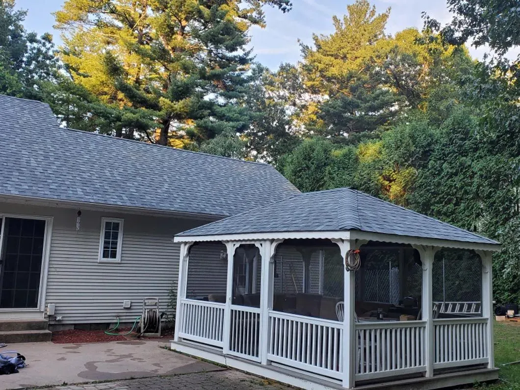 A gazebo with a screened in porch is in front of a house.