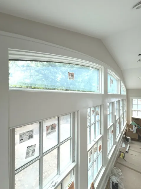 Cypress Works Massachusetts, an interior view of a room with large window frames and ongoing construction or renovation, including tools, paint cans, and cardboard boxes.