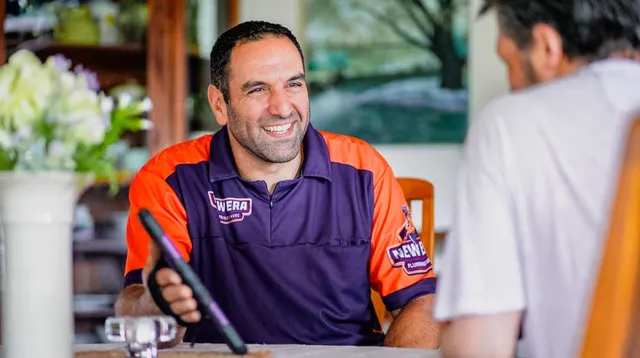 A New Era team member talks to a client while sitting at a table.
