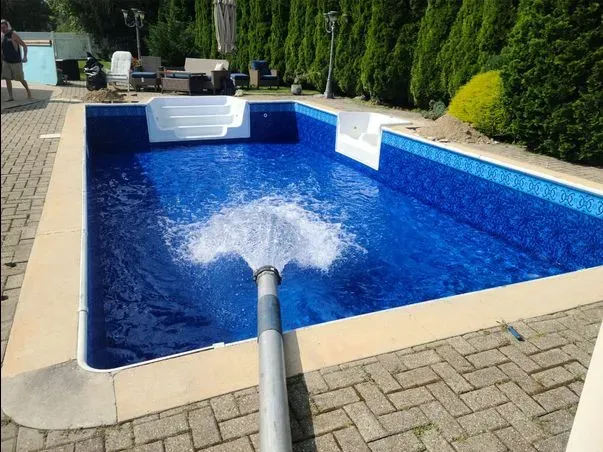 A swimming pool is being filled with water by a hose