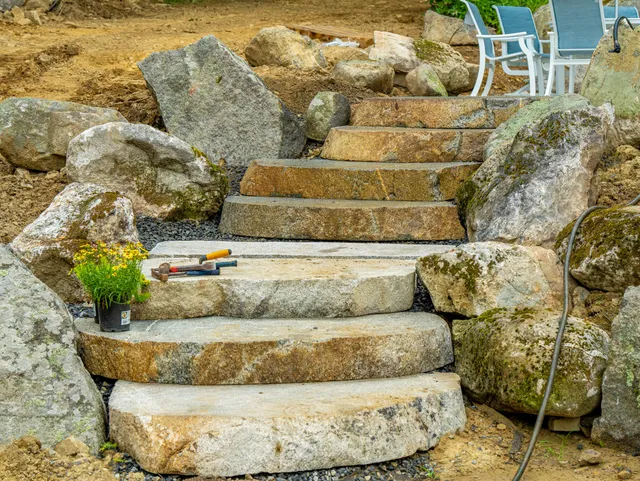 Rustic stone steps with boulders in landscaped yard