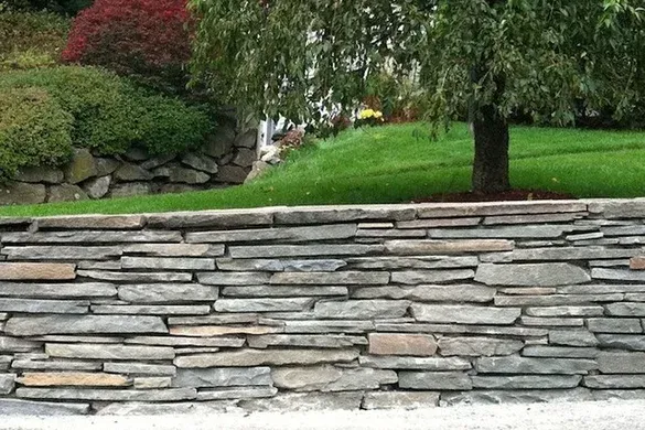 Dry-laid fieldstone retaining wall and lawn