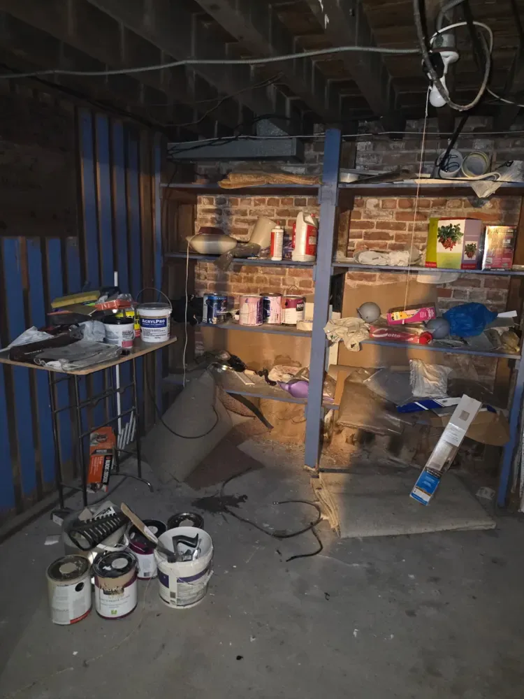 Basement shelves and floor covered with stored items before the cleanout