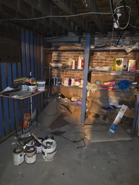 Basement shelves and floor covered with stored items before the cleanout