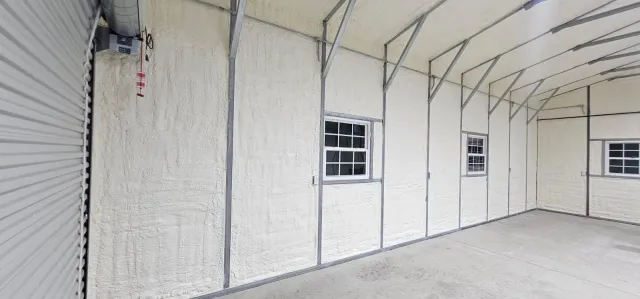 A large empty garage with white walls and windows.