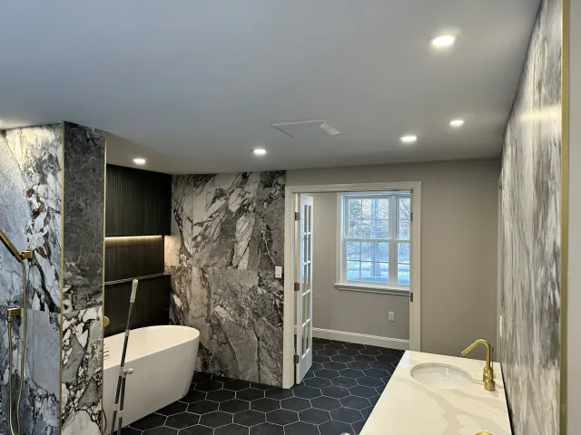 Renovated bathroom with recessed ceiling lighting and a lit shelf niche