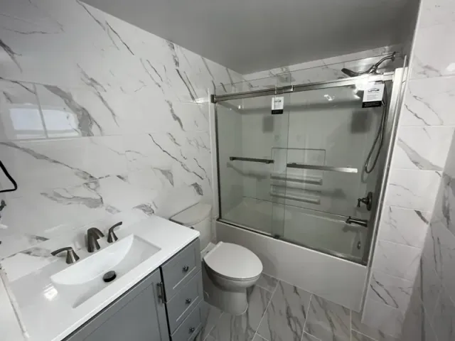 Finished bathroom with tiled walls, tub, vanity and toilet