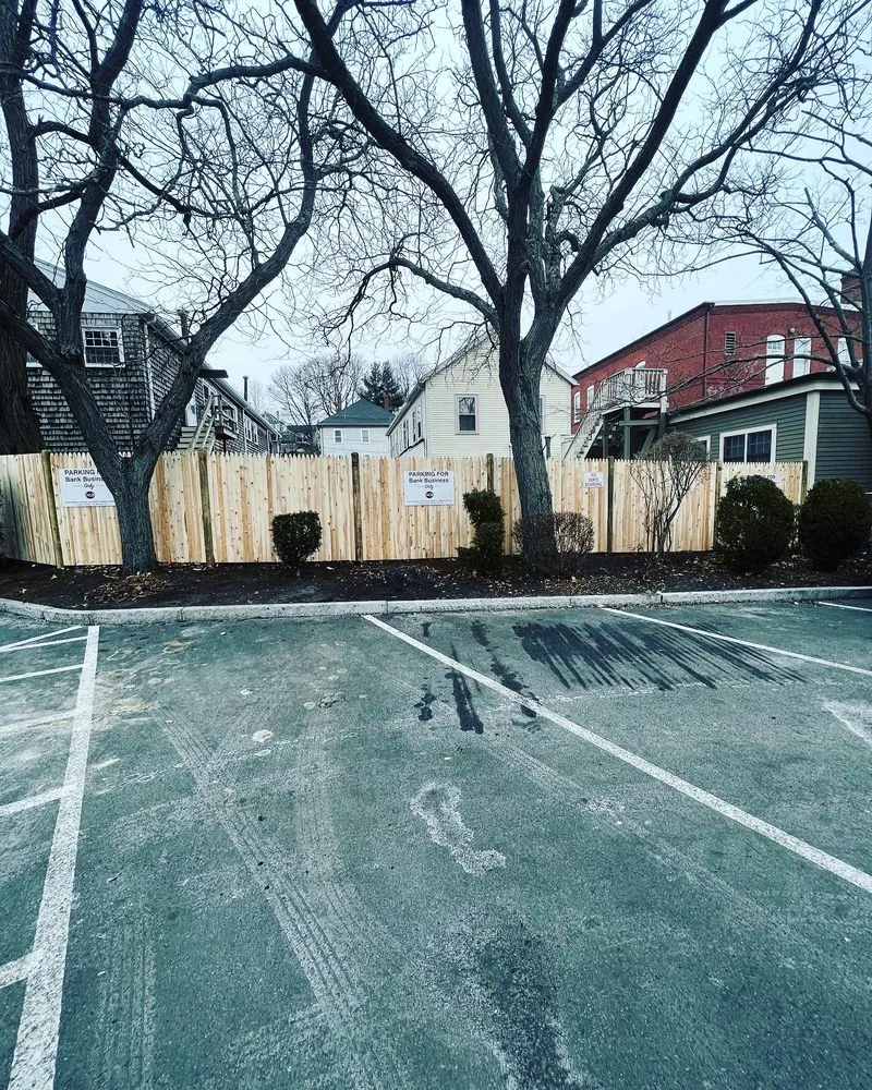 Completed cedar stockade fence enclosing a bank parking lot