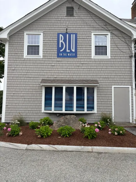 Blu Hair Spa exterior with blue sign, gray building, and floral landscaping.