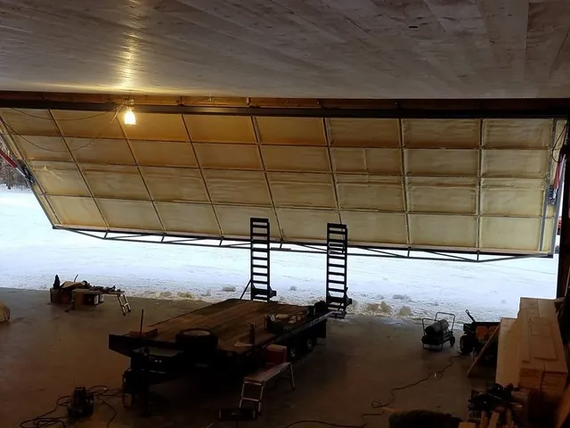 Overhead aircraft hangar door insulated with spray foam, with snow visible outside