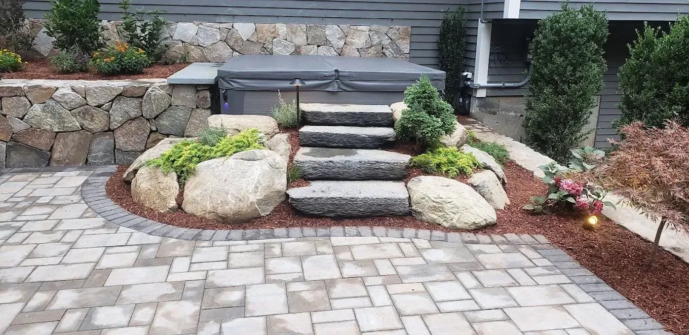 Stone steps leading through a landscaped front yard with rocks, shrubs, and paving stones