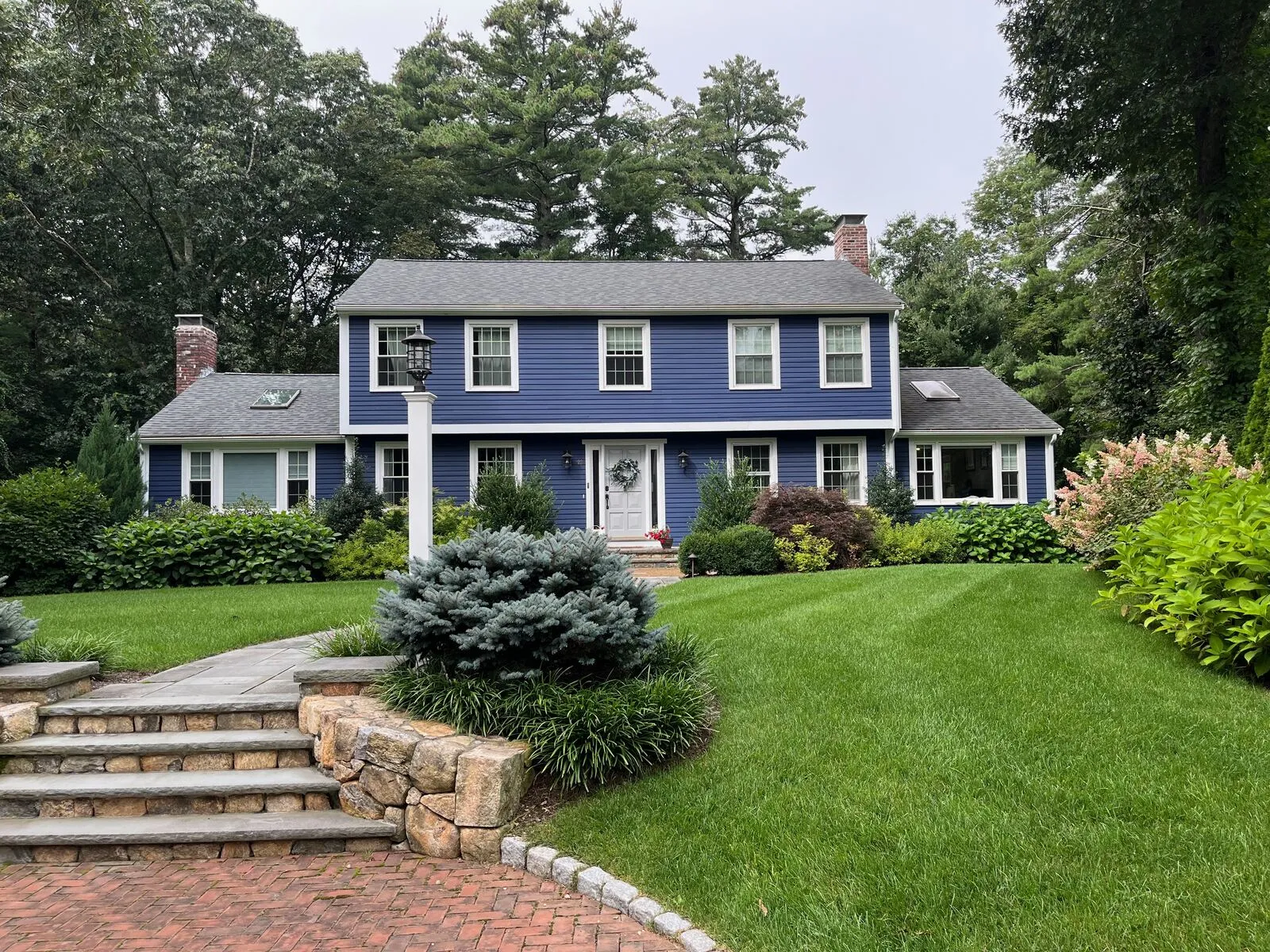 Architectural shingle replacement on a brick-faced Acton residence with extensive chimney and skylight flashing work.