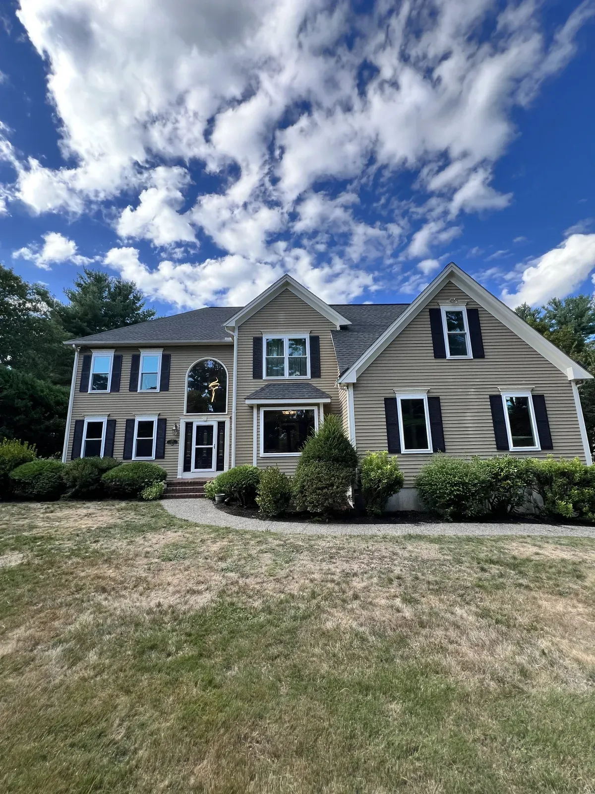 Colonial home with replacement windows under a cloudy sky